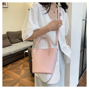 Close-up of light pink bucket bag with lychee texture leather and silver chain detail