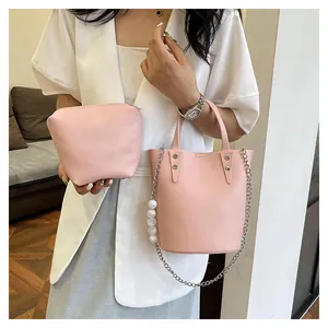 Detailed view of pink pebble leather bucket bag set with silver chain and large pearl accent