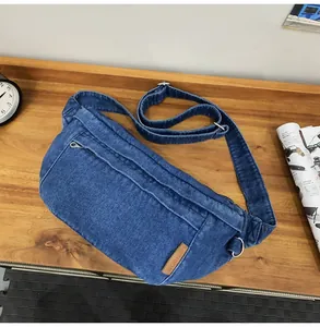 Detail van blauwe denim crossbodytas op houten tafel met textuur en zilveren ritsen