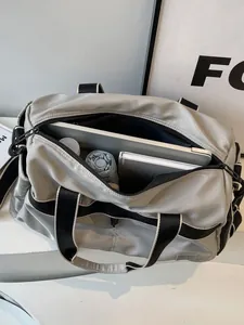 Reisetasche aus hellgrauem Nylon mit schwarzen Trägern, zeigt Stauraum und Innenfächer