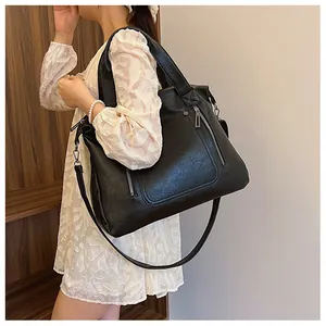 Détail macro du sac cabas en cuir noir montrant la texture souple et le zip argenté