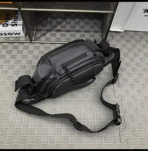 Detail view of large black tactical chest bag showing multiple zipper pockets and buckles