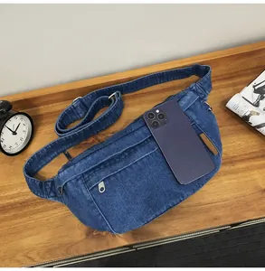 Detail van blauwe denim heuptas met ritssluitingen en grootte met een smartphone