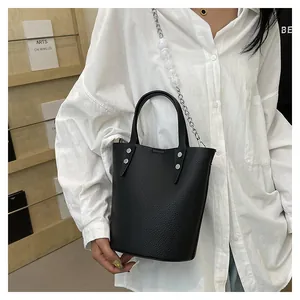 Detail of black pebbled leather bucket bag with oversized pearls on metal chain strap