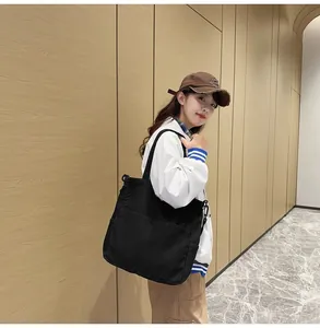 Dettaglio della borsa tote grande in denim nero con pratiche tasche frontali esterne