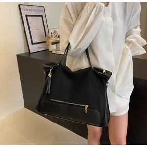 Detail of black canvas tote bag with gold zipper pocket and texture mesh paneling