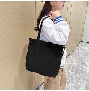 Dettaglio di una borsa tote in tela nera con tasche funzionali e ampi spallacci