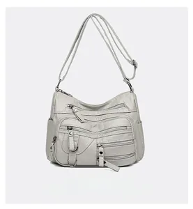 Vue détaillée du sac en similicuir gris montrant trois poches zippées et anneaux en métal