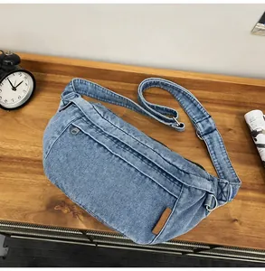 Detail van de blauwe denim borsttas met zilveren rits en bruin leren FASHION label