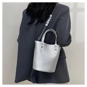 Detail of silver bucket bag with lychee texture, rivets, and decorative pearl metal chain