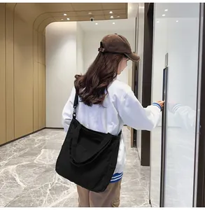 Dettaglio della borsa tote in tela nera con tasca laterale e doppia tracolla regolabile