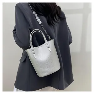 Detail of silver bucket bag showing pebbled leather texture and beaded chain strap