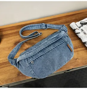 Detail van een gewassen denim crossbodytas met verstelbare riem op een houten tafelblad