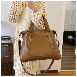 Sac cabas en similicuir marron avec zips frontaux porté par un mannequin en ville