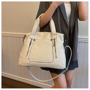 Détails de la texture du cuir crème et des zips décoratifs sur un grand cabas