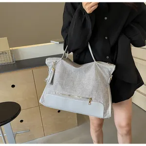 Detail of grey woven canvas tote bag with leather patchwork and tassel charm