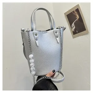 Close-up of silver bucket bag with lychee texture, metal chain and large pearl charms