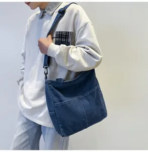 Dettaglio della borsa tote in denim blu con cuciture a contrasto e tracolla sulla modella