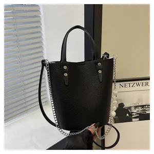 Detailed close-up of black litchi grain leather bucket bag with silver chain and bead strap