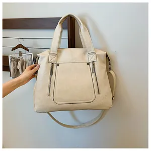 Détail d'un sac cabas beige avec texture en cuir souple et fermetures éclair vintage