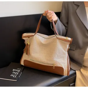 Detail of large canvas tote bag with brown leather trim and stylish fringe tassel