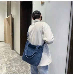 Dettaglio della grande borsa tote in denim blu scuro con cuciture e tracolla regolabile