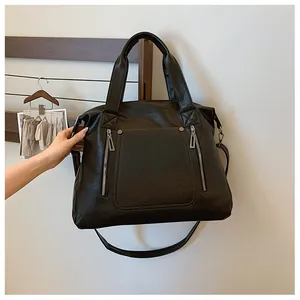 Détail du grand sac cabas noir en cuir texturé avec fermetures éclair et rivets en métal