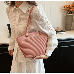 Close-up of pink pleated tote bag with golden metal rings and delicate shoulder straps