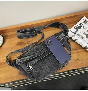 Detail van de vintage denim borsttas toont de capaciteit met een grote smartphone