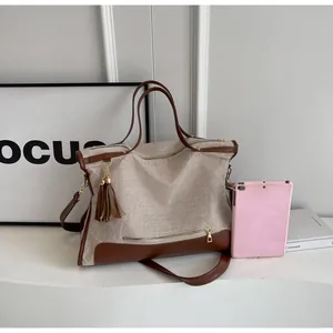Detail view of large canvas tote bag with brown leather trim and tassel showing internal space