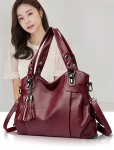 Detail of burgundy leather tote bag showing tassel charm and detachable shoulder strap