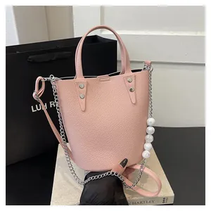 Pink lychee leather bucket bag featuring luxury white pearl chain and silver hardware