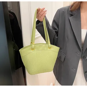 Detail of light green pleated tote bag featuring golden metal ring and soft PU leather