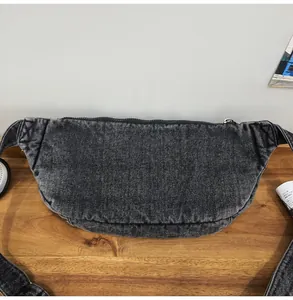 Detail van donkergrijze denim crossbodytas met zwarte rits en brede schouderriem