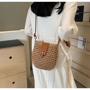 Détail du sac bandoulière en paille tressée avec rabat en cuir brun et boucle dorée