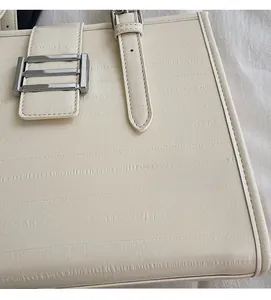 Close-up of cream textured leather tote showing silver metal buckle and croc pattern