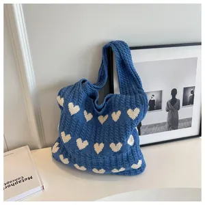 Nahaufnahme der blauen Stricktasche mit weißem Herzmuster und Zopfstrick-Textur-Details