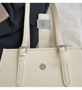 Detail of beige textured tote bag showing the silver magnetic buckle and strap adjustment