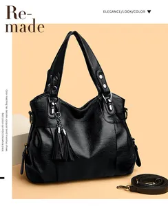 Detail of black pebbled leather tote bag with fringe tassel and metallic rivet accents