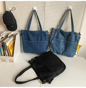 Dettaglio di grandi borse tote in denim blu e nero con doppie tasche frontali