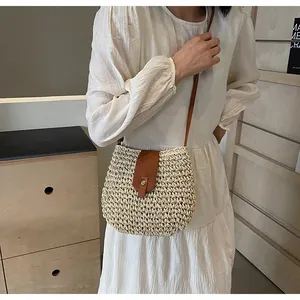Détail du sac bandoulière en paille tressée avec rabat en cuir brun et boucle dorée