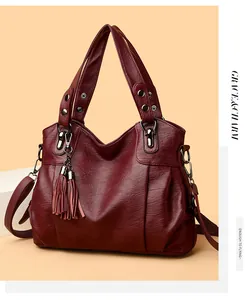 Detail view of burgundy leather tote bag featuring tassel charms and retro metal hardware