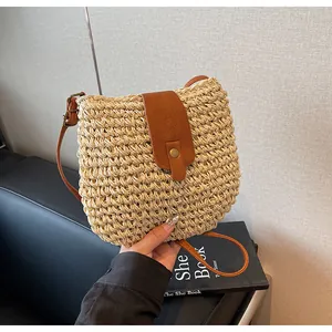 Détail du sac en paille tressée avec rabat en cuir marron et boucle en métal rétro