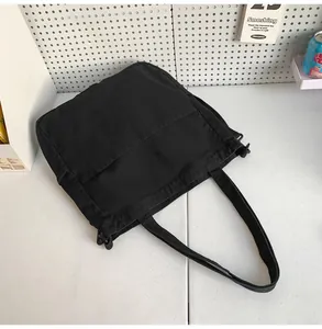 Dettaglio della borsa tote nera in tela con due tasche frontali e trama del tessuto denim