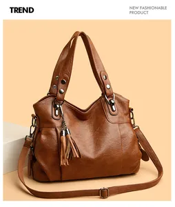 Detail of a brown leather tote bag with tassel charm and vintage hardware finish