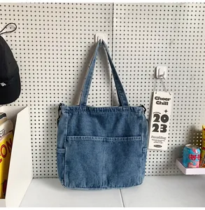 Dettaglio ravvicinato della borsa tote in denim blu con tasche anteriori e cerniera