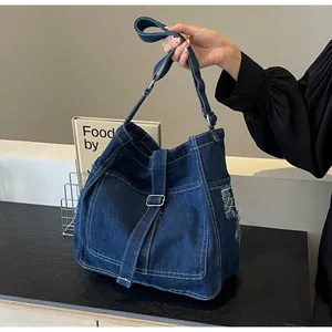 Close-up of large blue denim tote bag with contrast stitching and frayed pocket detail