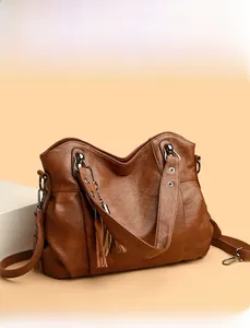 Detail view of dark brown faux leather tote bag with tassel accent and pleated design