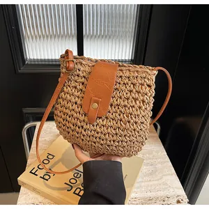 Gros plan du sac en paille tressée avec rabat en cuir marron et bouton pression doré