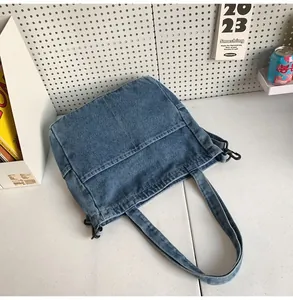Dettaglio della borsa tote in denim blu scuro con fibbia in metallo e tasca anteriore
